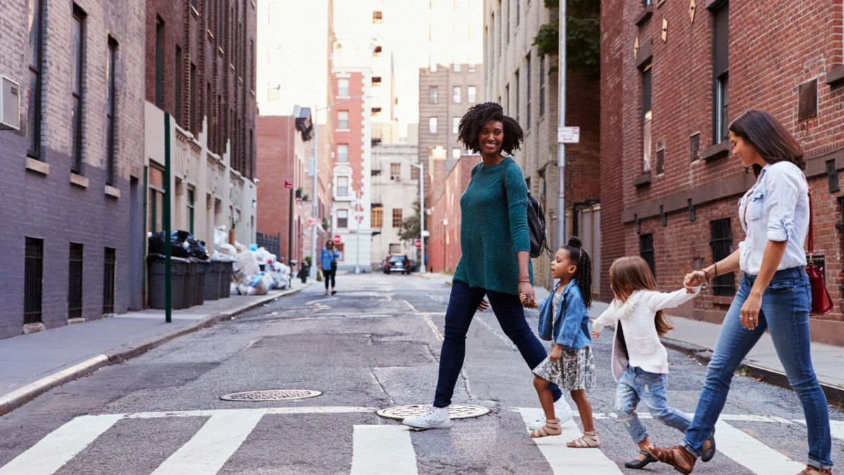 Two mother friends with two daughters crossing the road.