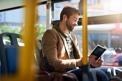 Cropped shot of a handsome young man reading a book during his morning bus commute.