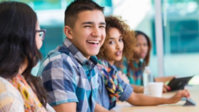 Young male student smiling while sitting with other students