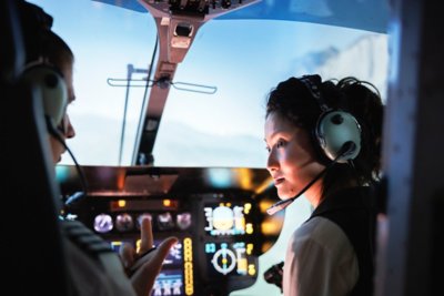 Pilot in discussion with copilot in cockpit in evening