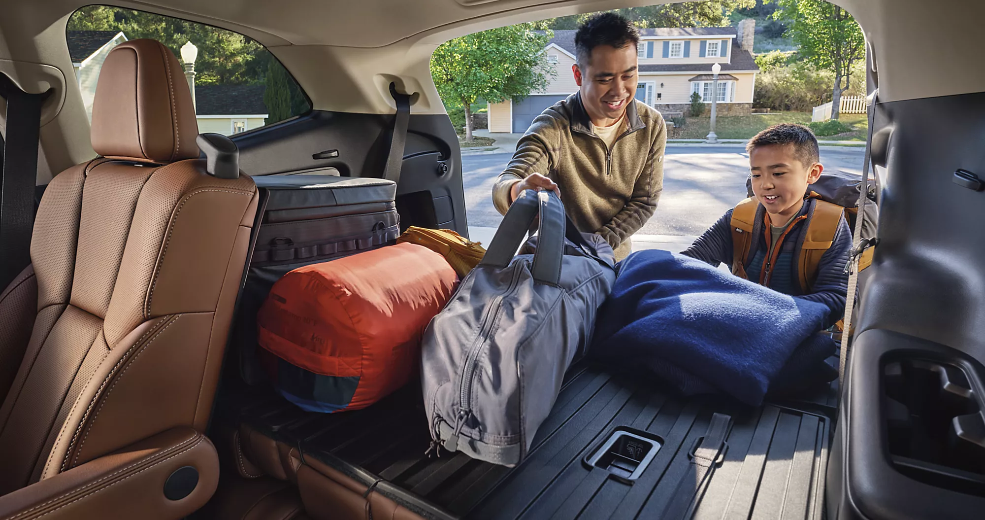 Father and child packing the folded down backseat/trunk with multiple camping luggage of 2024 Subaru Ascent with tan interior