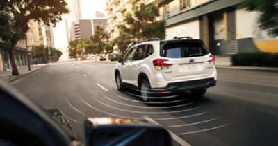 White 2025 Subaru SUV parked outside of brick industrial building with palm trees and succulent landscaping