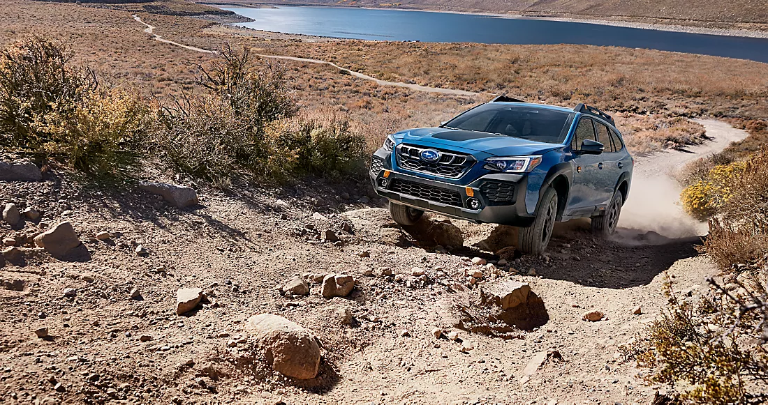 Blue 2024 Subaru wilderness outback rock climbing in heavy rocky terrain.