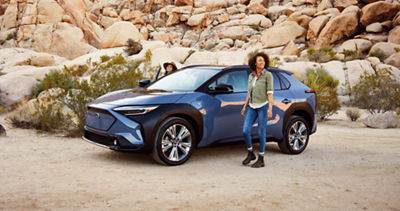 Pareja junto a su SUV Solterra 2023 de 5 asientos en un sendero desértico.