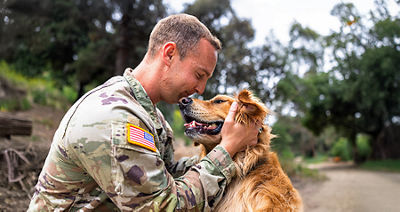 Un veterano con uniforme abraza a su perro.