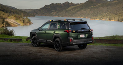 2026 Subaru Outback in dirt parking lot overlooking a scenic lake.