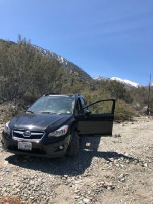 A dark Subaru Outback parked on a gravel road
