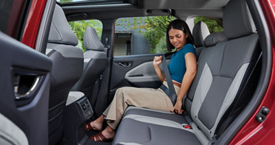 A woman buckles her seatbelt in the rear passenger seat of a 2026 Subaru Forester.