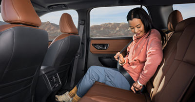A woman sitting in the backseat of a 2026 Subaru Outback midsize SUV.