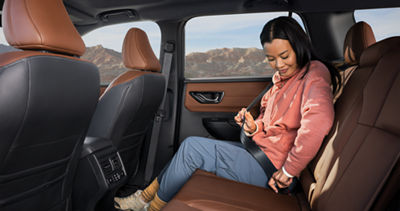 A woman sitting in the backseat of a Subaru Outback midsize SUV