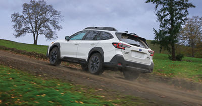 A white Subaru Outback Onyx Edition drives on a dirt road.