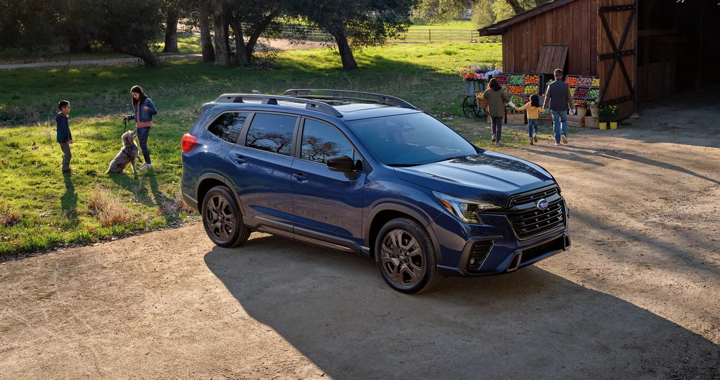 A blue Subaru Ascent parked on a gravel drive as children play nearby