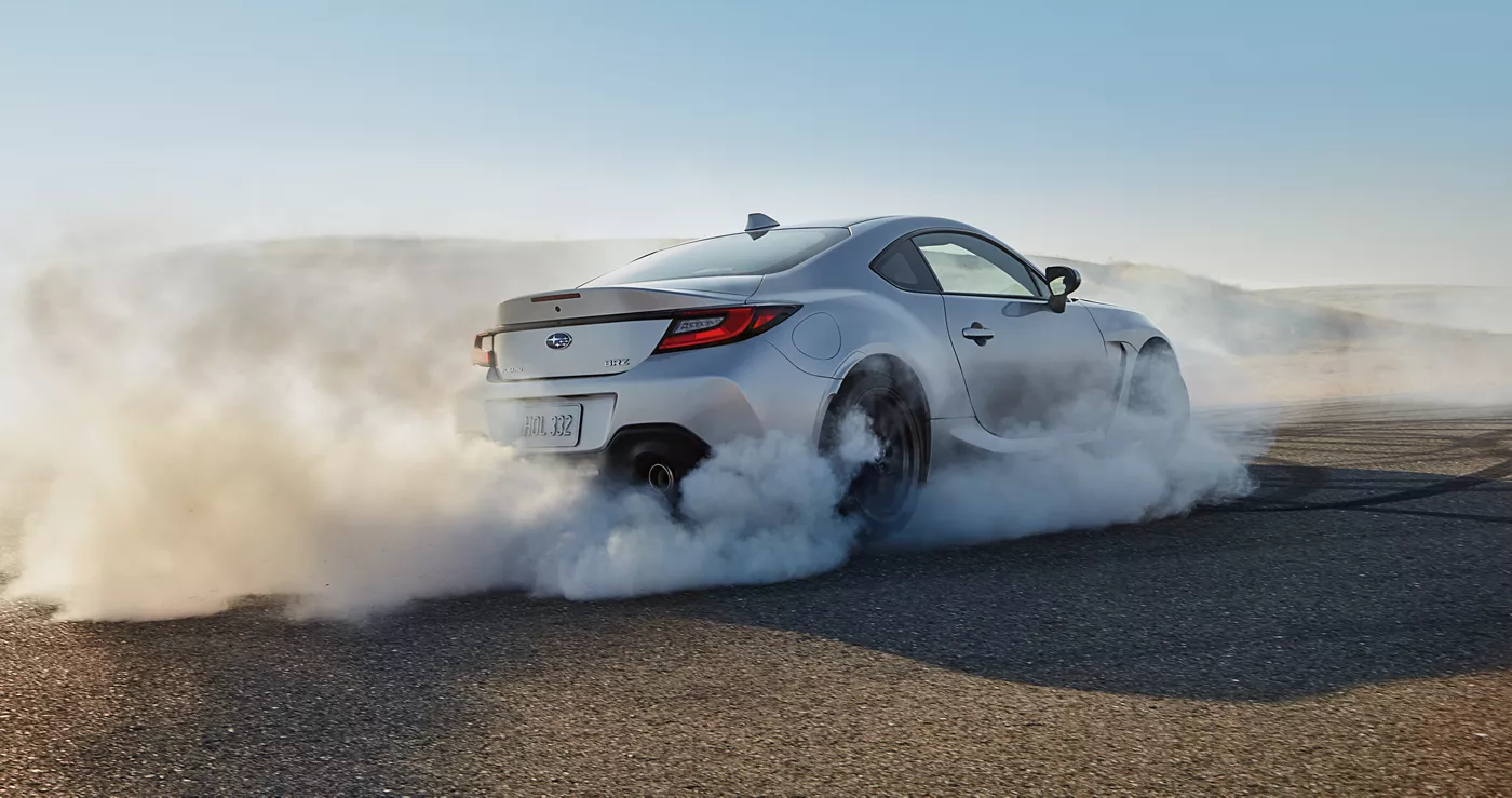 A silver Subaru BRZ in a cloud of tire smoke