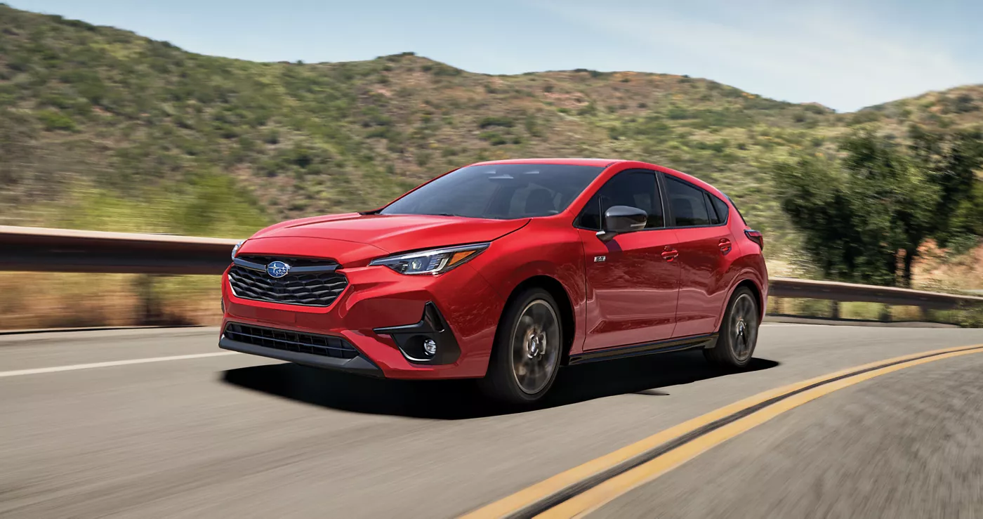 A red Subaru Impreza on a winding coastal road