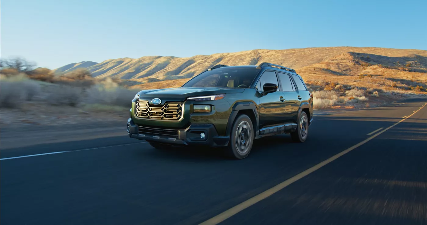 A green Subaru Outback on a desert highway