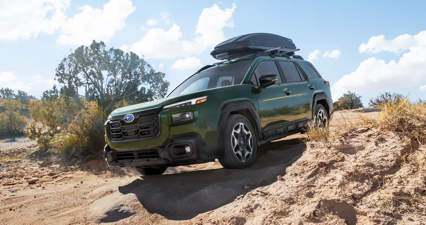 A green Subaru Outback parked on red rock