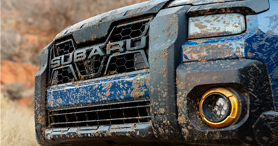 Blátem potřísněná přední maska a světlomety modrého Subaru Outback Wilderness 2026.