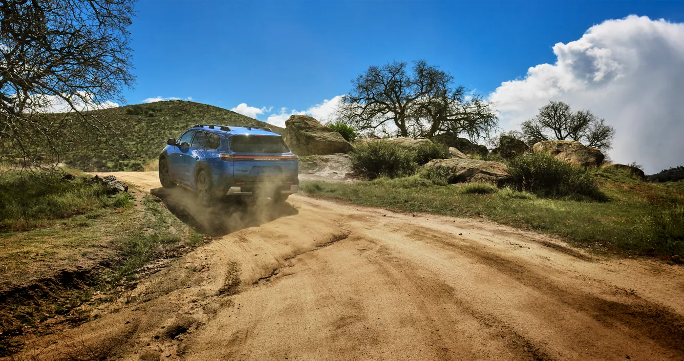 A blue Subaru Trailseeker climbing a dirt road