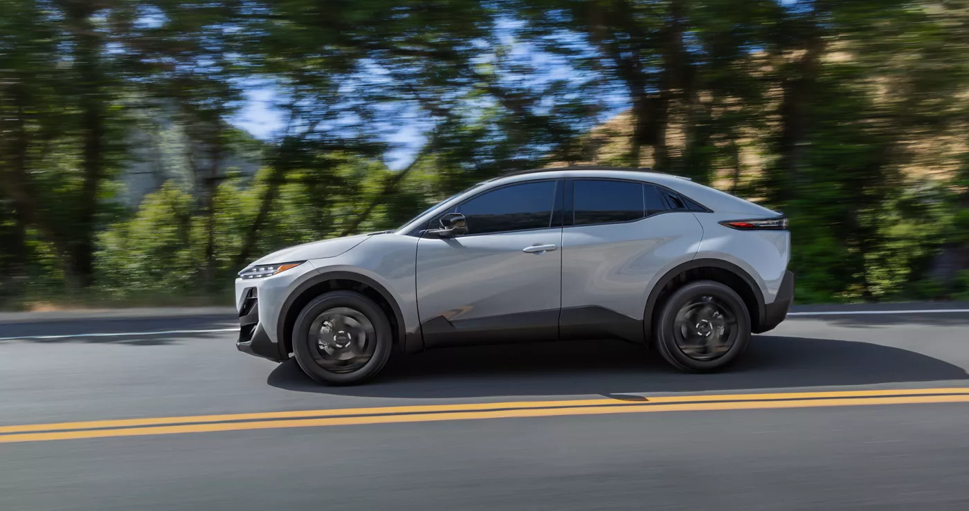 A silver Subaru Uncharted in profile on a tree-lined road