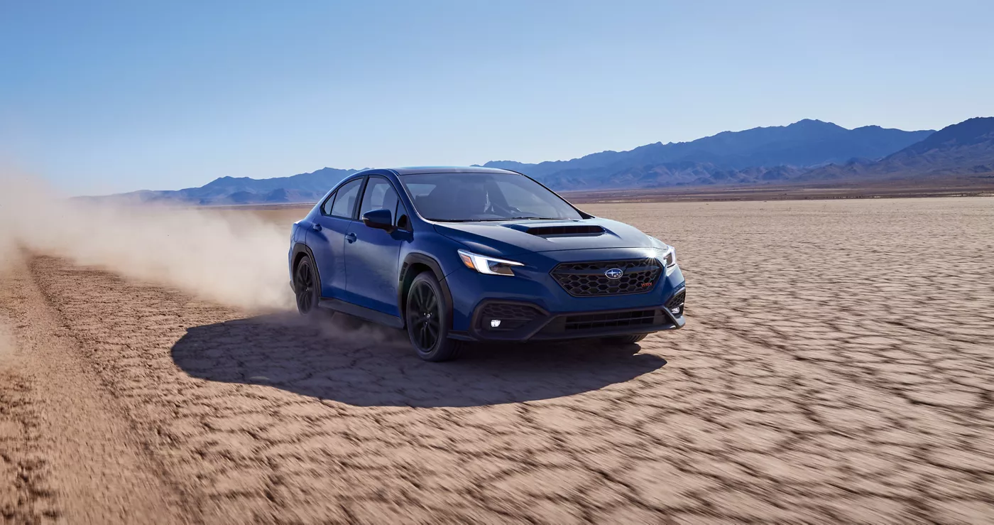 A blue Subaru WRX on a dry lake bed