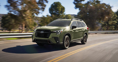 A 2027 Subaru Ascent SUV drives on a country road.
