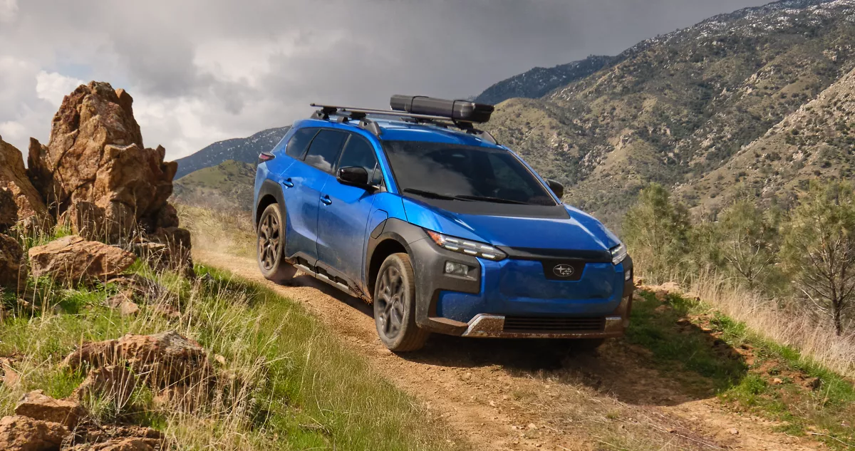 Blue Subaru Trailseeker with a roof rack on a mountain trail