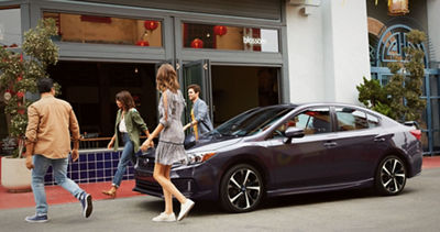 Impreza 2020 estacionado en una calle de la ciudad, con un grupo de adultos jóvenes entrando a una tienda.