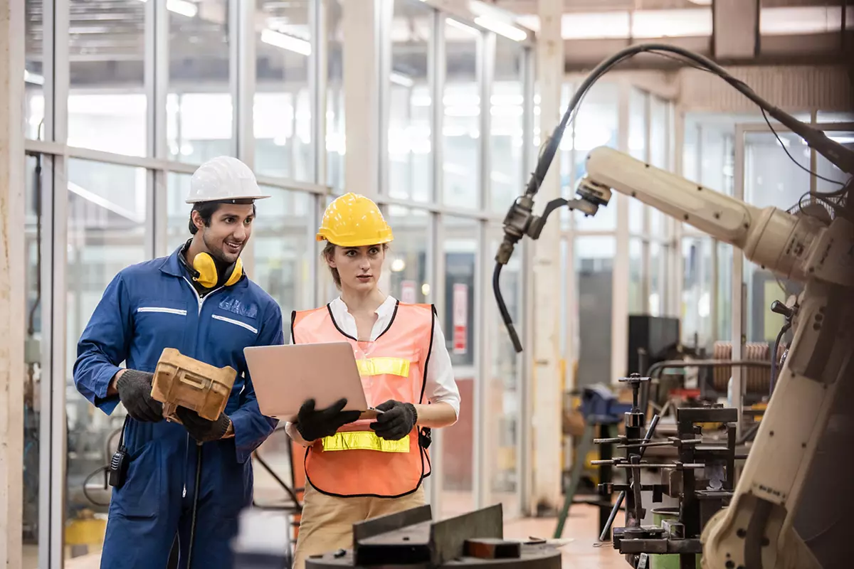 Engineer and worker control and check robot working in factory. The worker is controlling the robot to work in the factory.