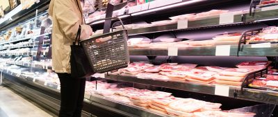 femme dans un supermarché comparant de la viande sous emballage