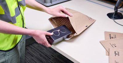 warehouse worker packing eyeglasses in paper bubble mailer