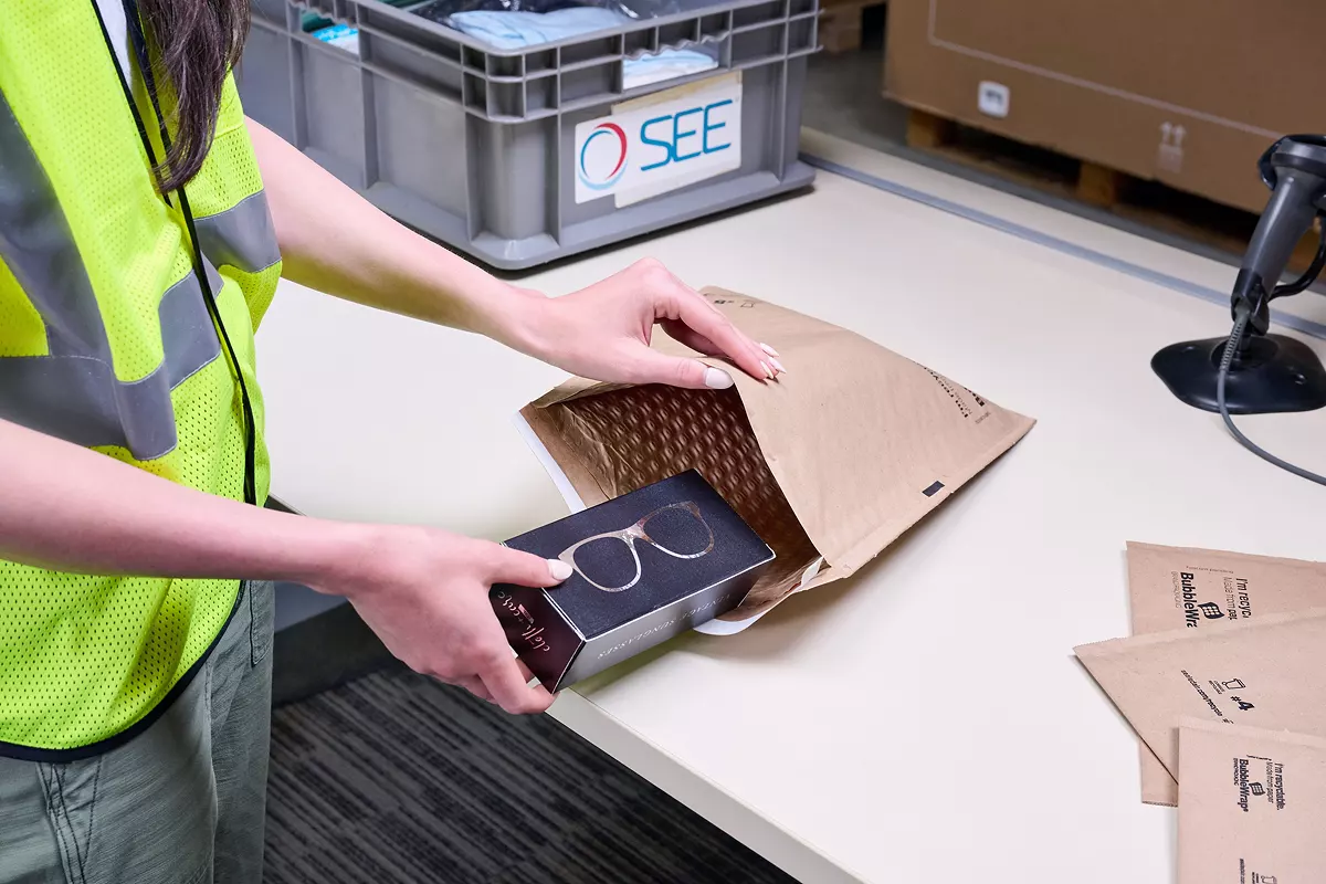 warehouse worker packing eyeglasses in paper bubble mailer