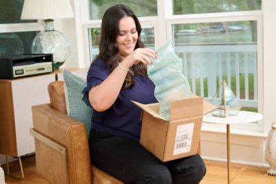 A woman sits in a chair with a box in her lap