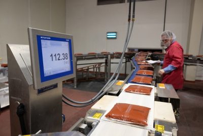 worker weighing bags on a conveyor belt