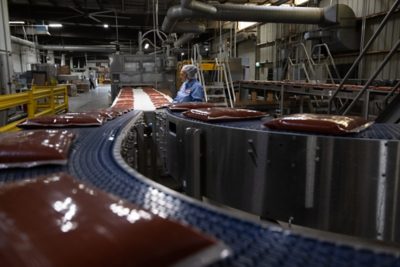 conveyor with flexible pouches containing tomato sauce