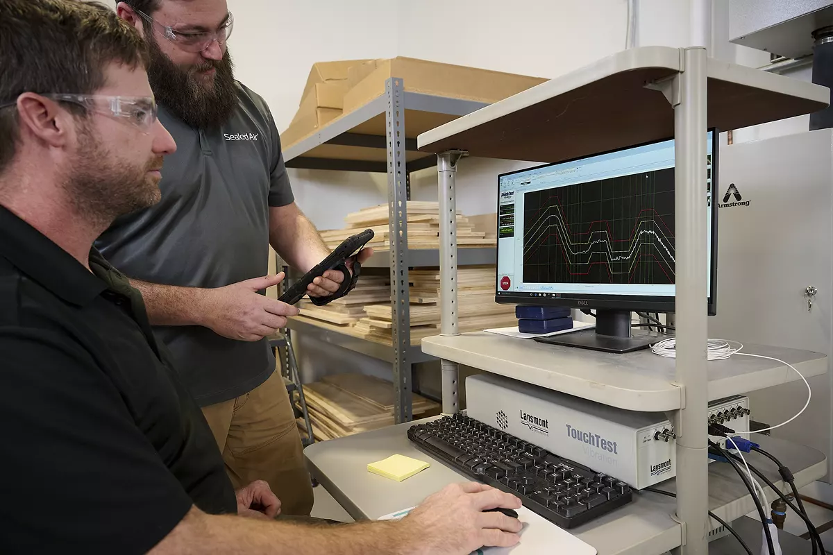 two engineers using a computer to perform package testing