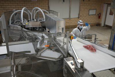 worker moving meat on a conveyor belt
