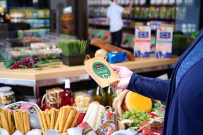 woman holding block of cheese in grocery store