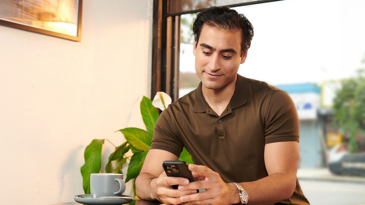 Man works on his phone in a coffee shop.