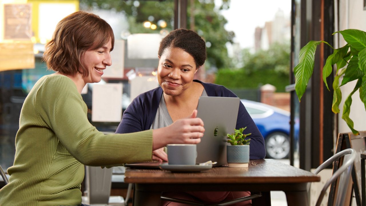 two women collaborate in front of a laptop