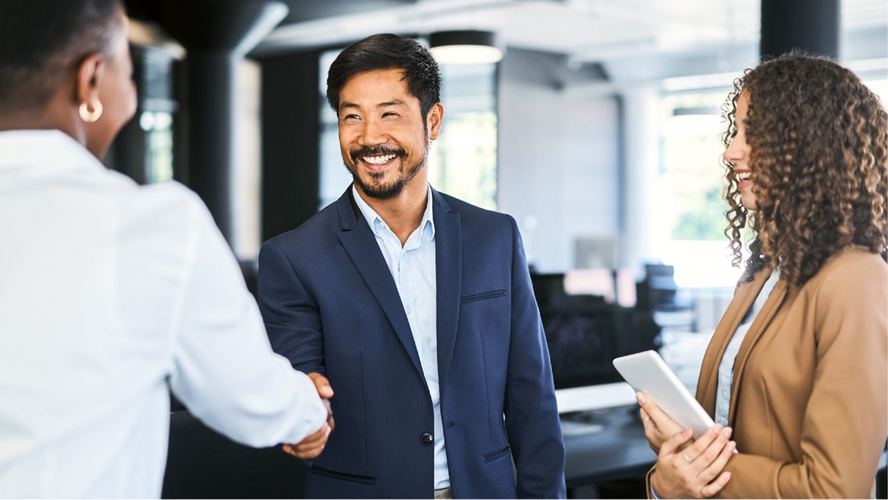 Two professionals shake hands and smile