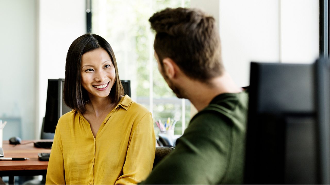 Manager smiling at her direct report during a meeting.