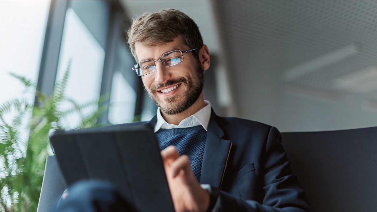 businessman smiles while using tablet computer