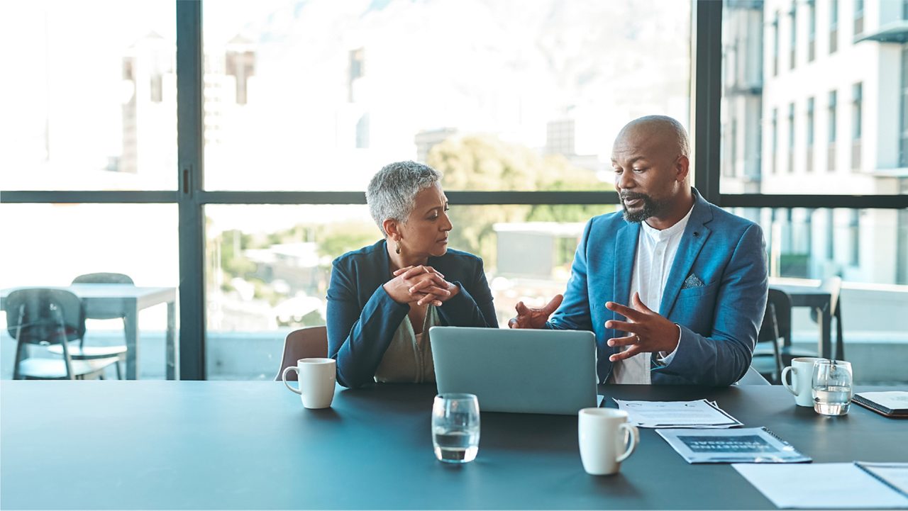 a man and a woman discussing over a laptop in a modern office