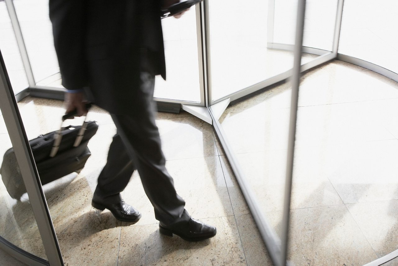 Businessman with suitcase using revolving door