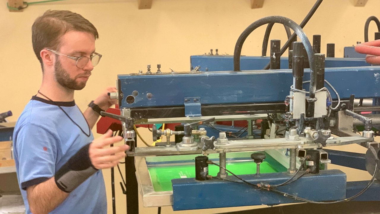 Jeremy Duggan, one of many workers with autism at Spectrum Designs, sets up the screen printing press.