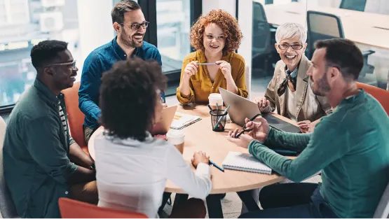 coworkers smiling sitting around a round table