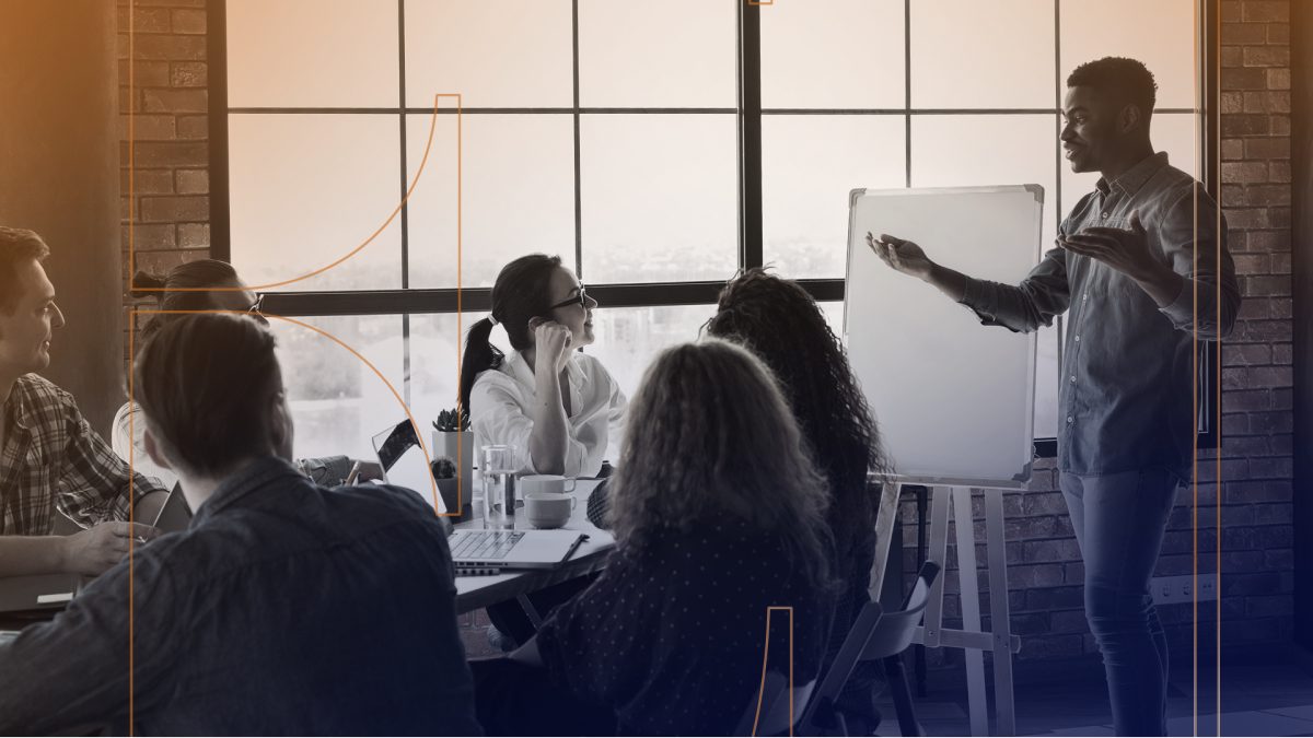 Employees in a meeting talking excitedly next to whiteboard.