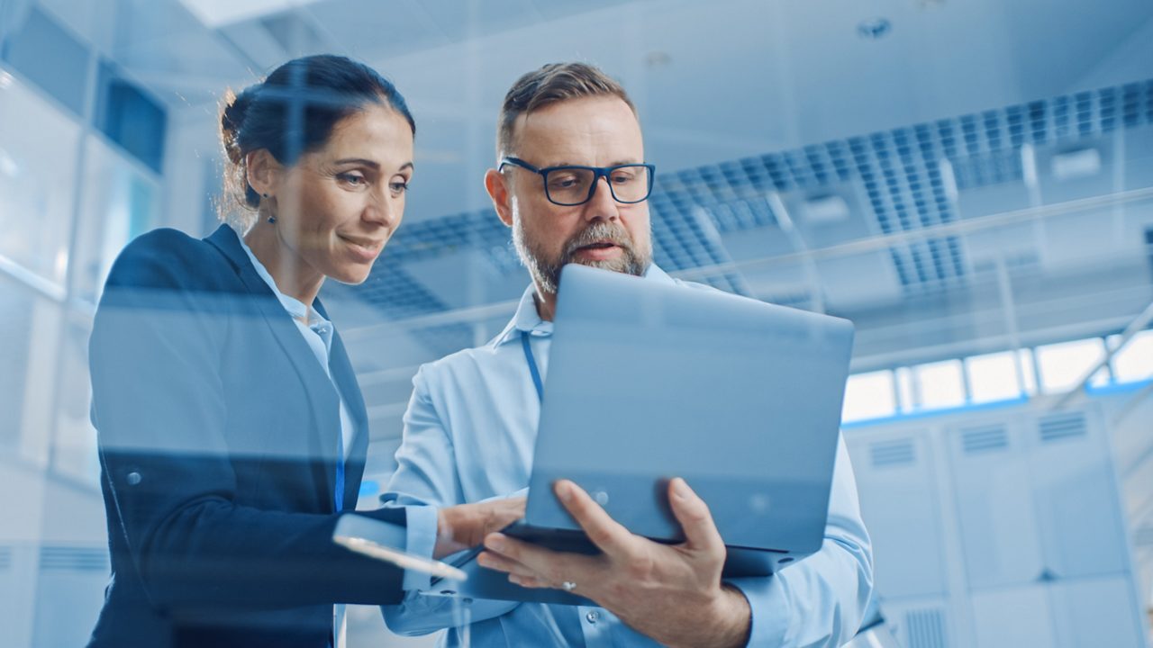 Two people actively engaged with a tablet device against a futuristic background