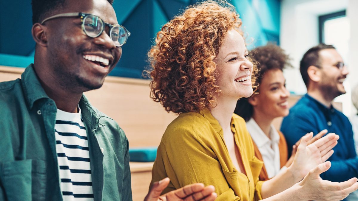 Employees laugh and clap at a conference