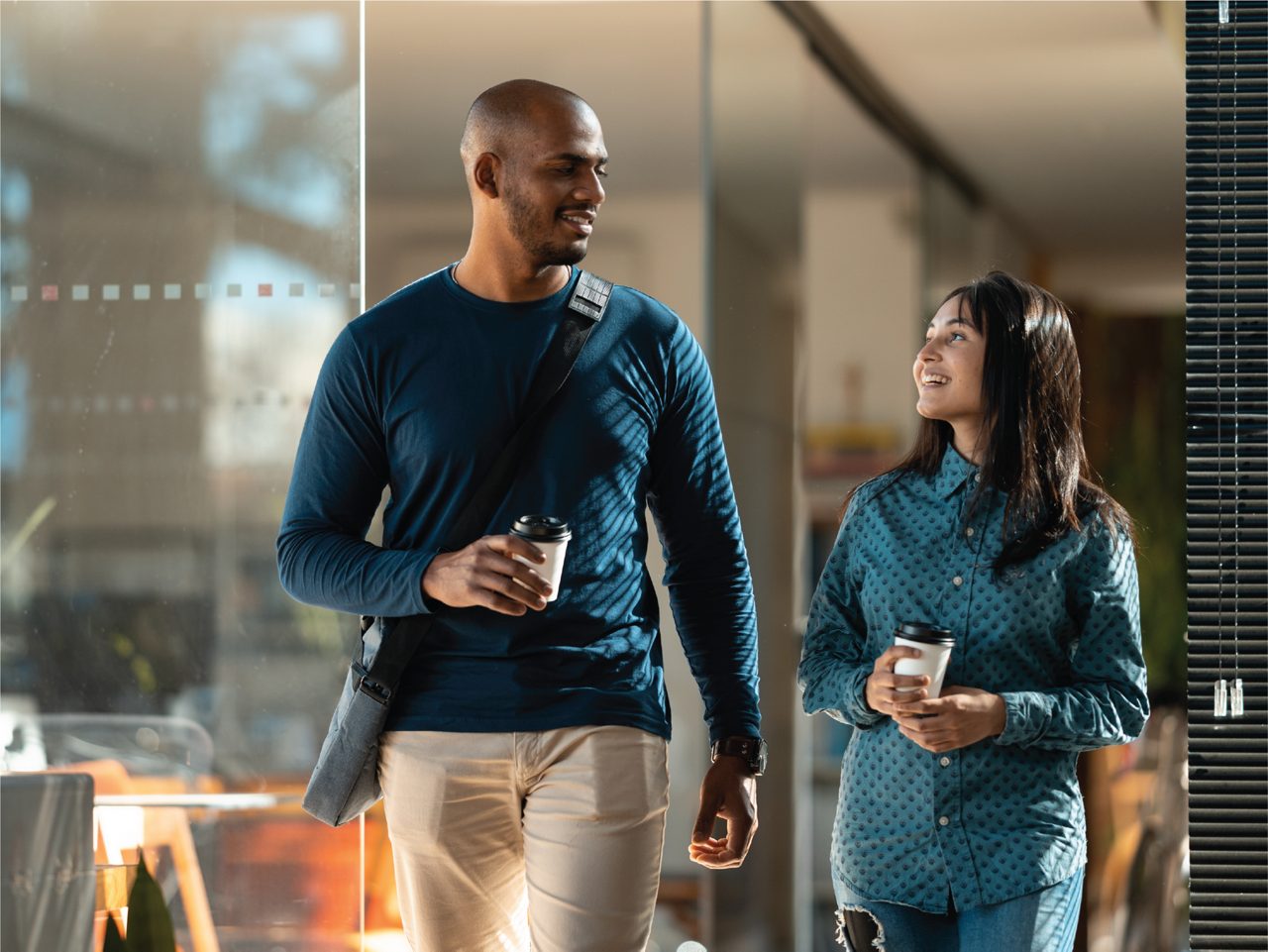 man and woman walking and smiling in a modern office